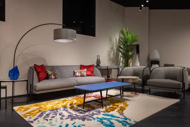 Cream rug with abstract splashes of blue, purple and yellow under a blue coffee table
