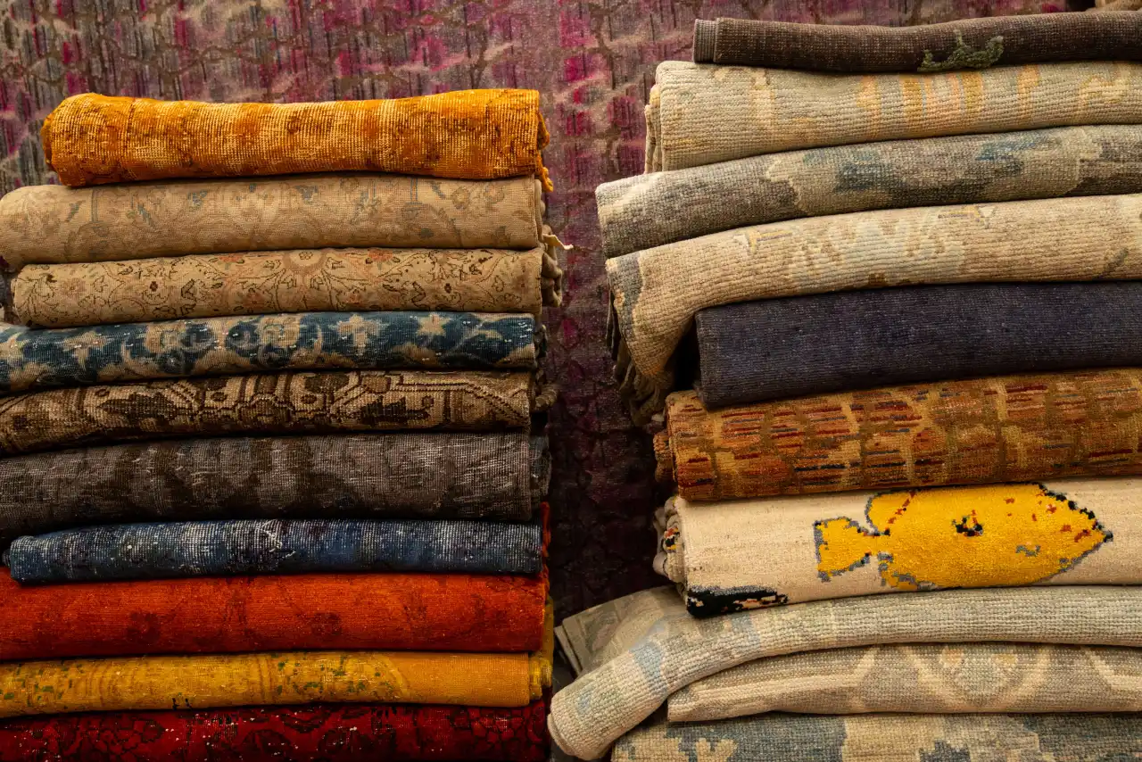 Two stacks of folded vintage rugs in rust, indigo, ochre and faded rose